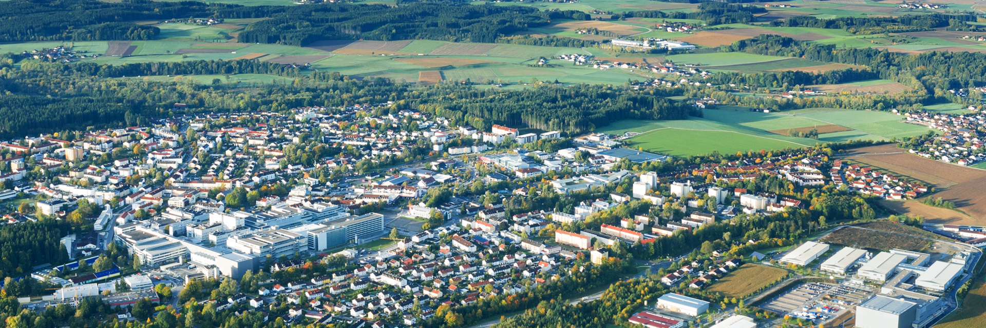Weitläufige Luftaufnahme des Firmengeländes und der umliegenden Stadt Traunreut